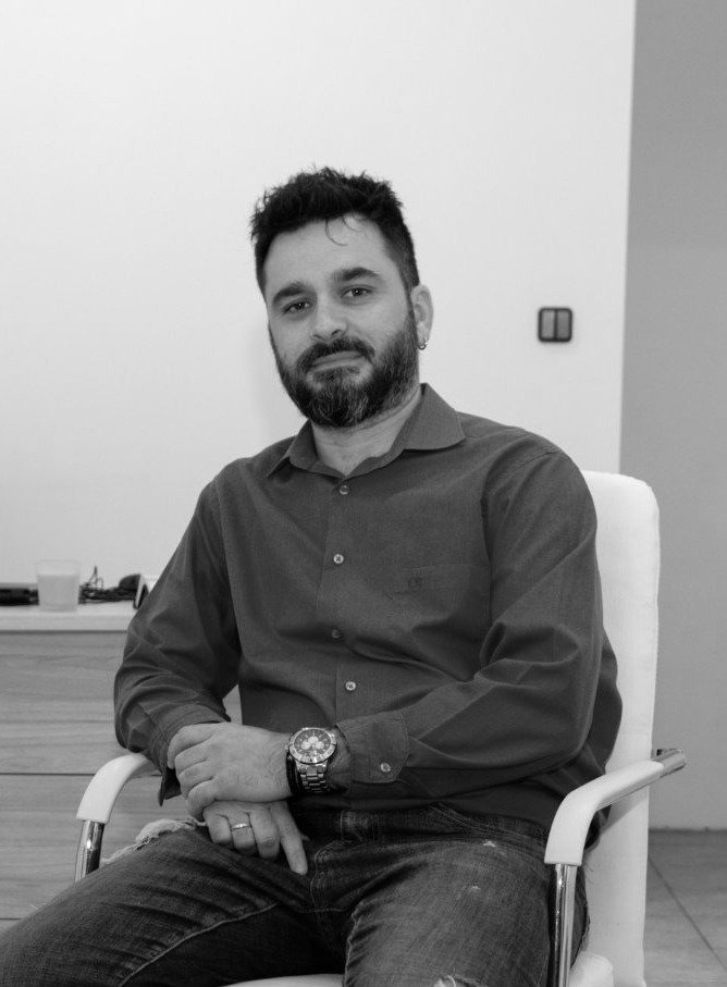 Ο Σωτήρης Ντατσόπουλος, σύμβουλος ψυχικής υγείας, καθισμένος σε λευκή πολυθρόνα μέσα στο γραφείο του
